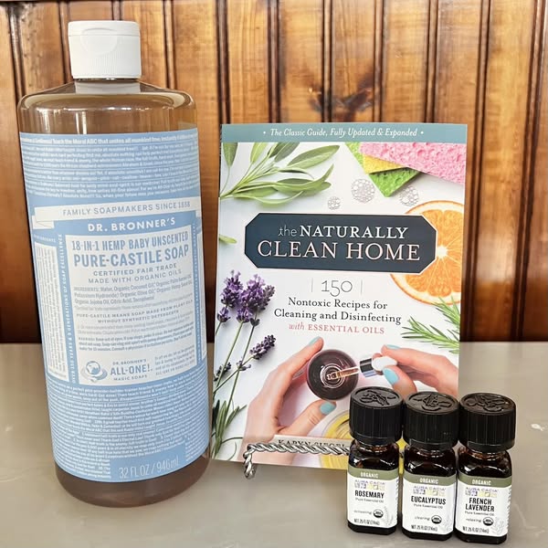 Pictured: Dr. Bronner castile soap, the Naturally Clean Home recipe book, and 3 Aura Cacia Essential oils.